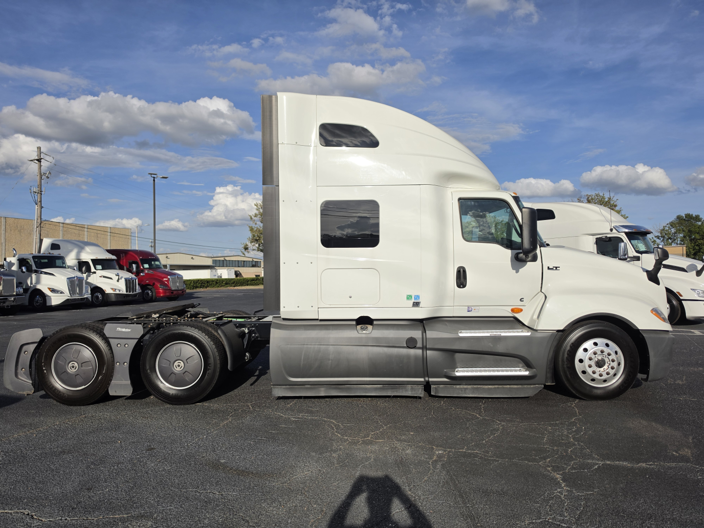 Truck side profile showing 2023 International LT625 sleeper cab with white exterior, two rear axles, and gray lower panels.