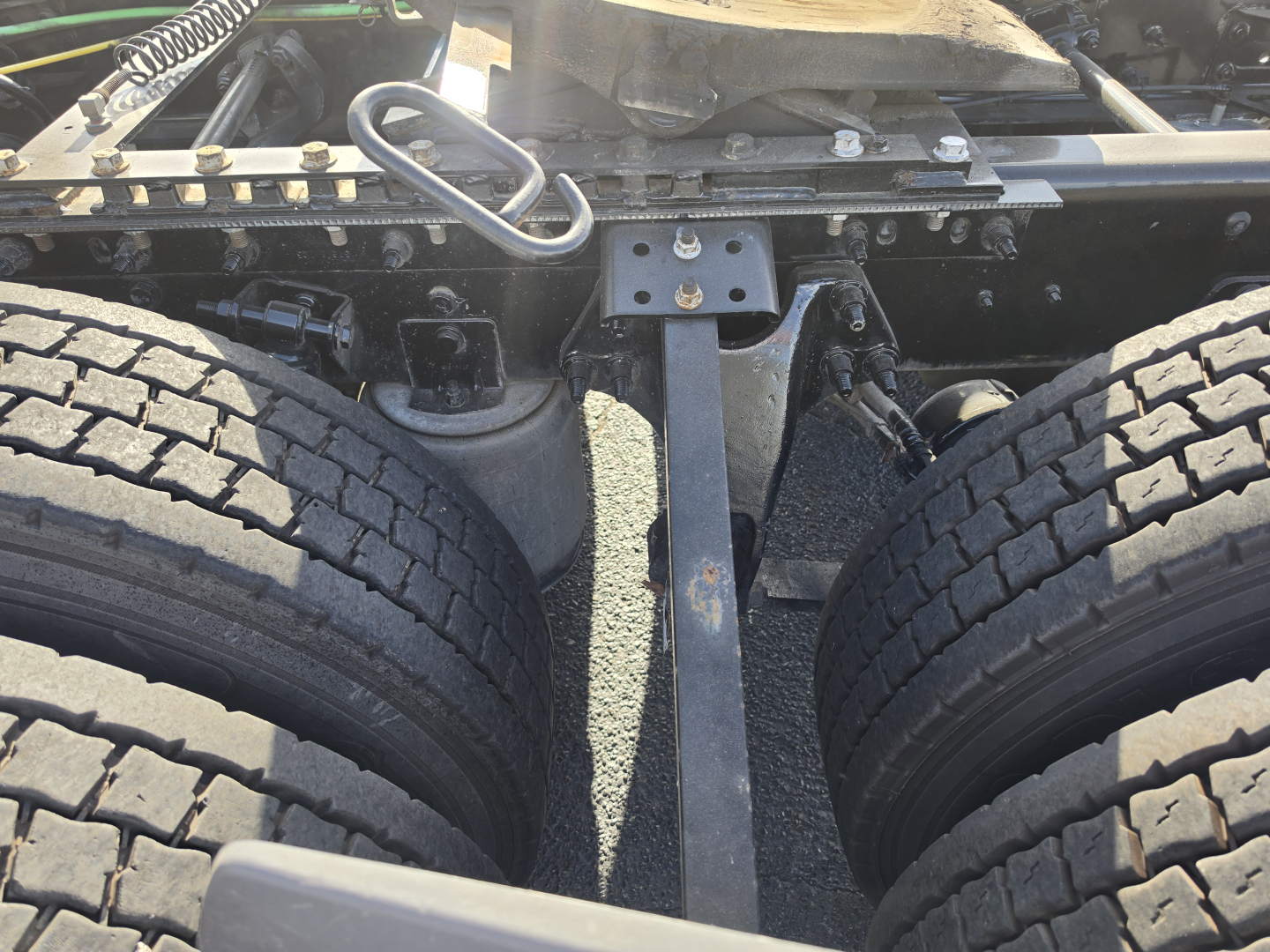 Truck chassis and dual rear tires in view showing frame, suspension, and hitch area of a 2023 International LT625 in-service, with visible leaf spring and mounting hardware.