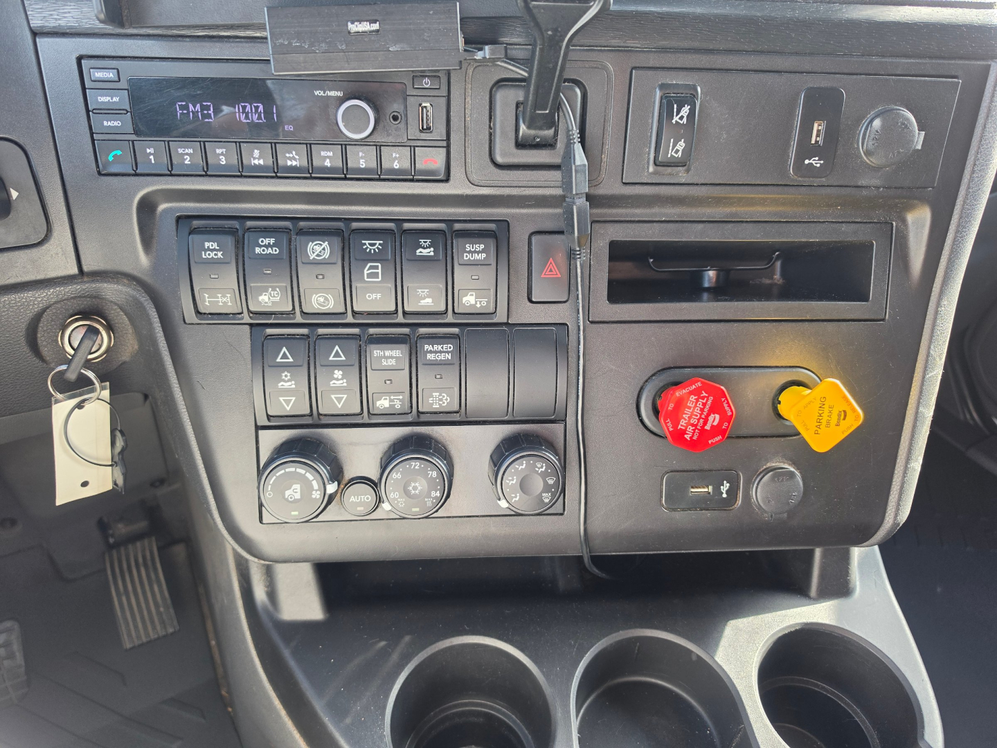 Dashboard panel of a 2023 International LT625 truck showing control switches, climate knobs, radio display, and emergency/drive controls.
