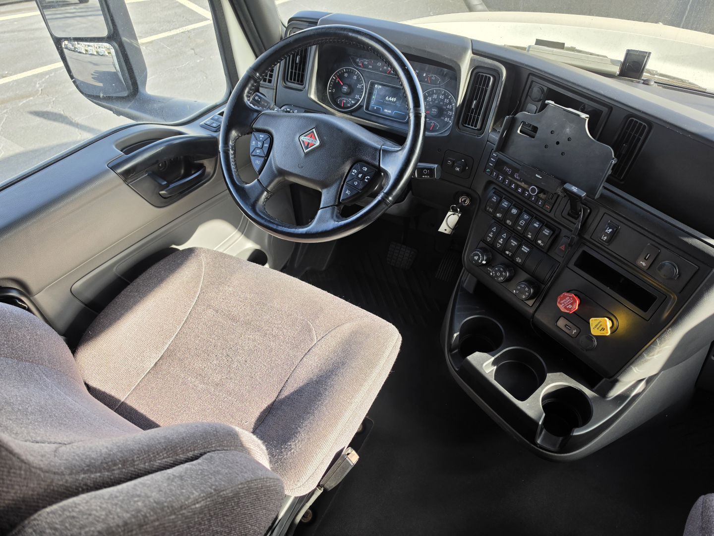 Interior of a 2023 International LT625 showing steering wheel, dashboard, and center console with controls and cup holders.