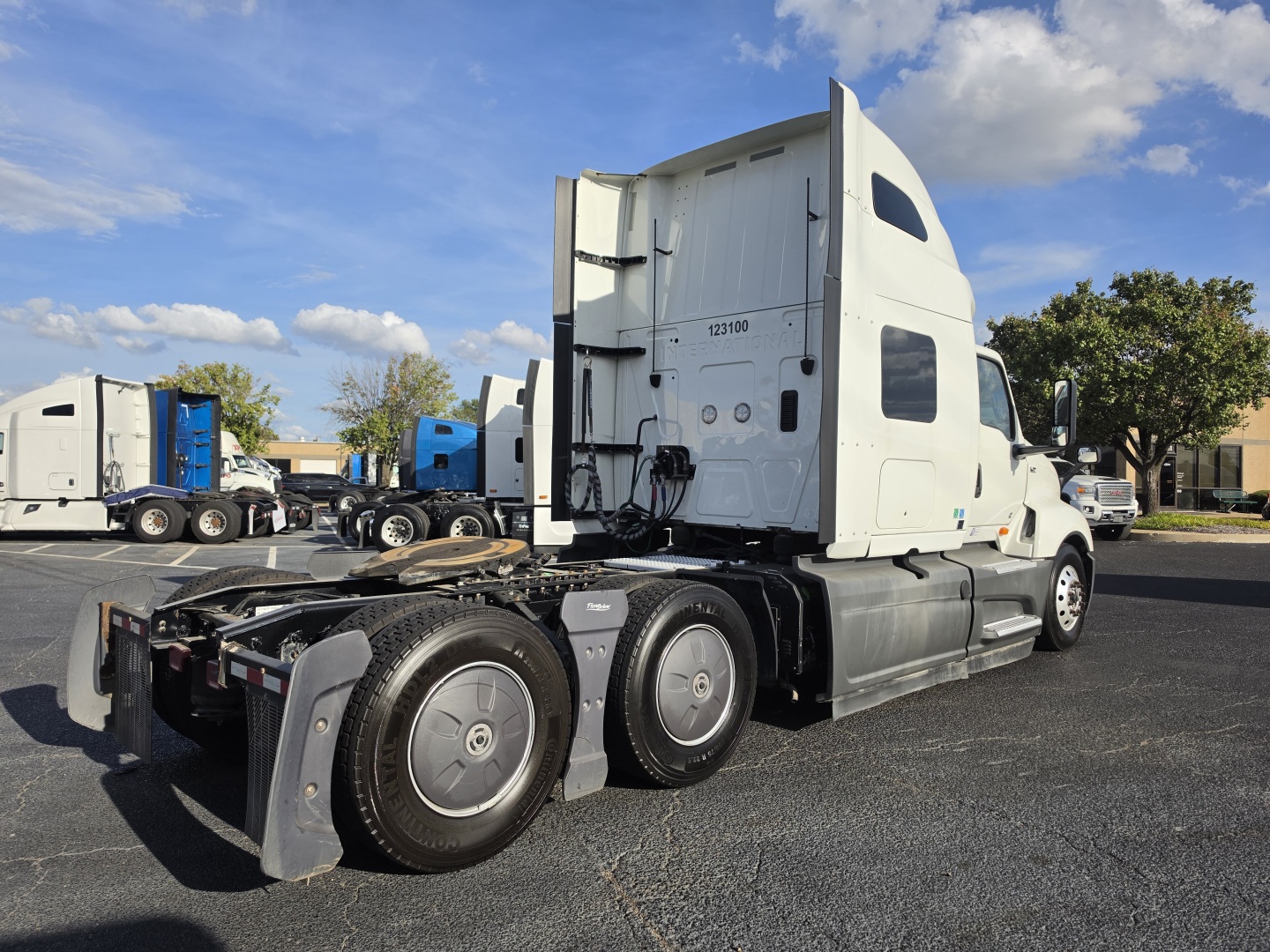 Truck: 2023 International LT625 sleeper tractor in a parking lot, side view showing rear wheels, fifth wheel, and cab with exhaust stacks; no visible damage.
