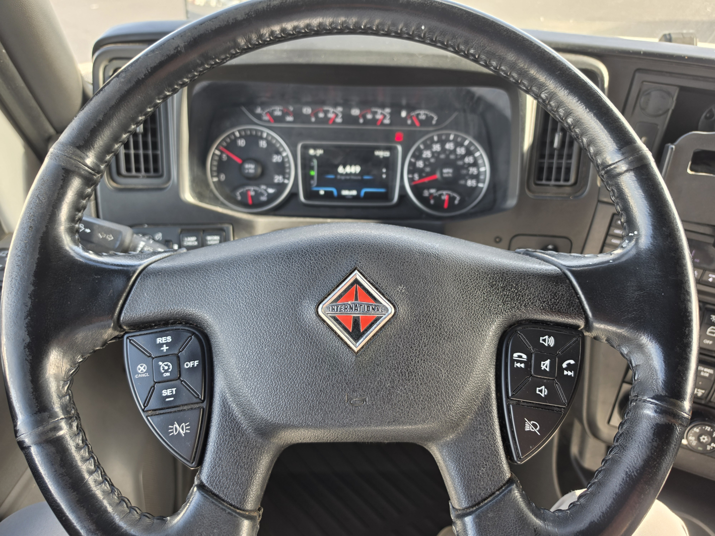 Truck steering wheel and dashboard of a 2023 International LT625 showing instrument cluster and controls in the steering wheel.