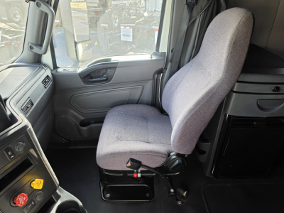 Truck interior cab seat and dashboard of a 2023 International LT625 truck showing driver seat, dashboard, and storage compartments.