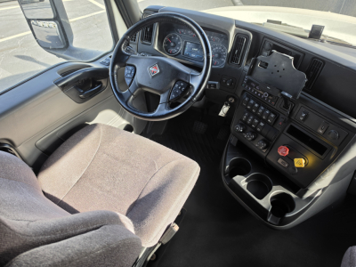 Interior of a 2023 International LT625 showing steering wheel, dashboard, and center console with controls and cup holders.
