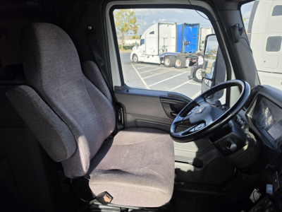 Interior of a 2023 International LT625 truck cab showing driver seat and steering wheel.
