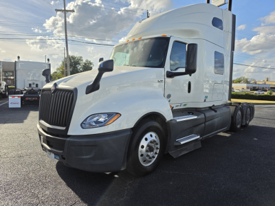 International LT625 daycab sleeper tractor in white from left front view showing front grille, hood, cab mirrors, and tandem rear axles.