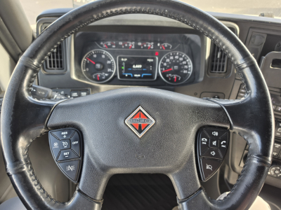 Truck steering wheel and dashboard of a 2023 International LT625 showing instrument cluster and controls in the steering wheel.