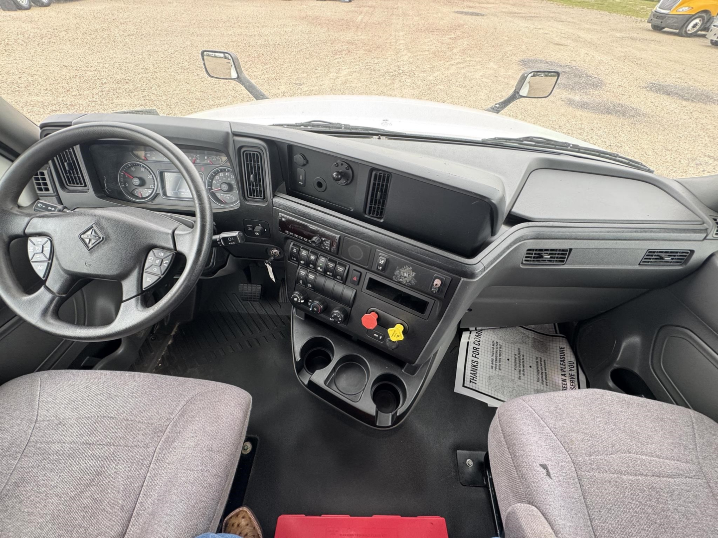 Interior of a 2021 International LT cab showing steering wheel, dashboard, central control panel with gauges, vents, cup holders, and seats.