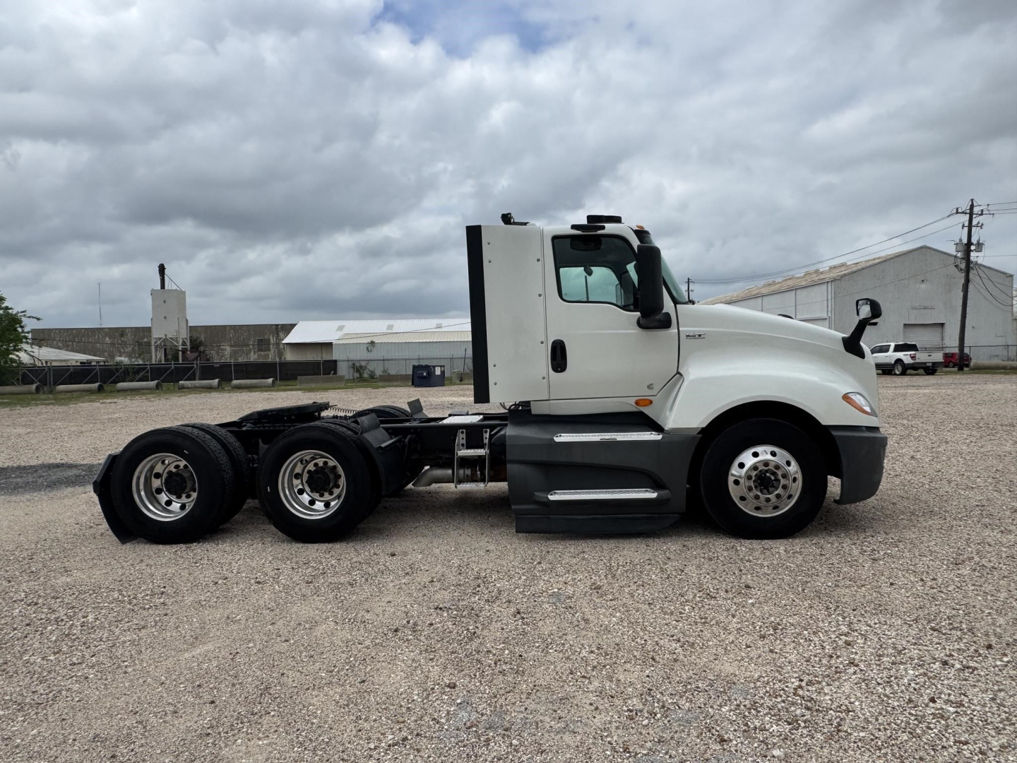 Truck side view showing 2021 International LT conventional daycab with three-axle rear, white cab, black chassis, and fuel tanks; VIN 3HSDZAPR0MN079000 visible in listing.