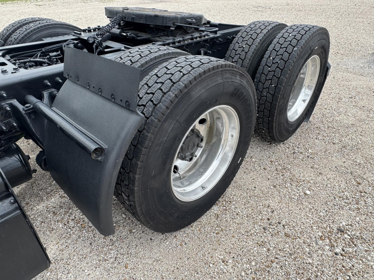 Truck rear dual-axle setup with heavy-duty mudflaps and twin rear wheels, chassis framing, and fifth wheel mounting area visible.
