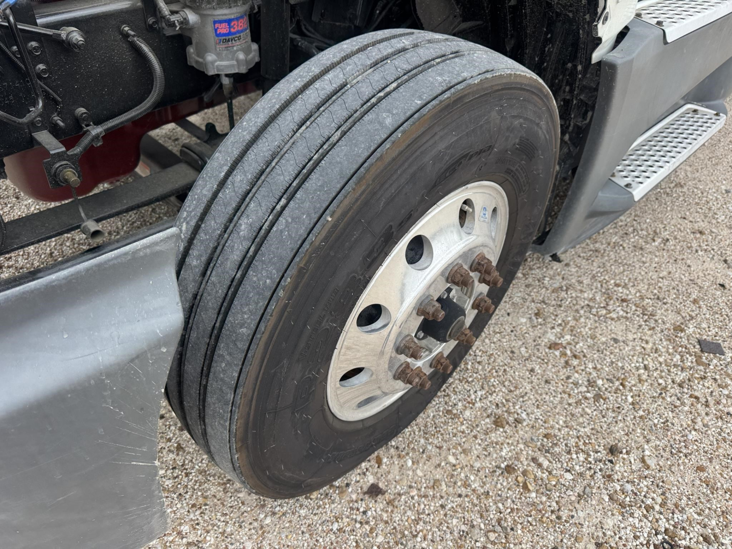 Truck wheel and front suspension of a 2021 International LT conventional daycab showing heavy-duty dual rear tires, hub, and step platform.