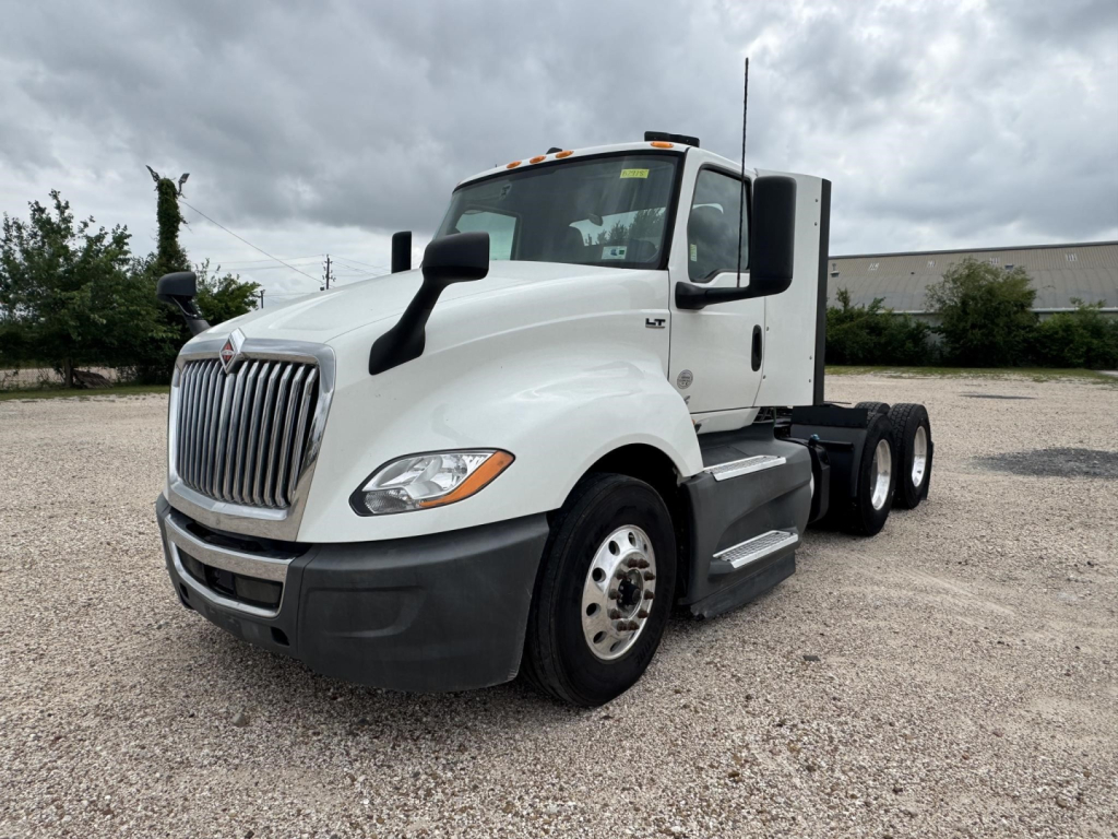 Truck cab exterior with white International LT daycab, front grille, side mirror, and dual rear axles visible.