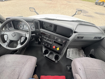 Interior of a 2021 International LT cab showing steering wheel, dashboard, central control panel with gauges, vents, cup holders, and seats.