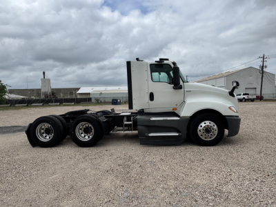 Truck side view showing 2021 International LT conventional daycab with three-axle rear, white cab, black chassis, and fuel tanks; VIN 3HSDZAPR0MN079000 visible in listing.