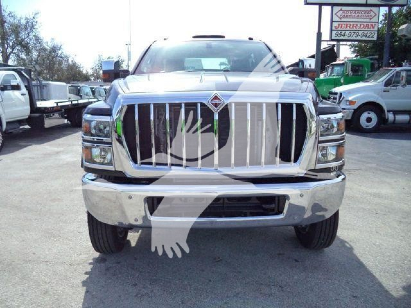 Front view of a white 2023 International CV truck with chrome grille, bumper, and visible headlights; dealership lot in background.