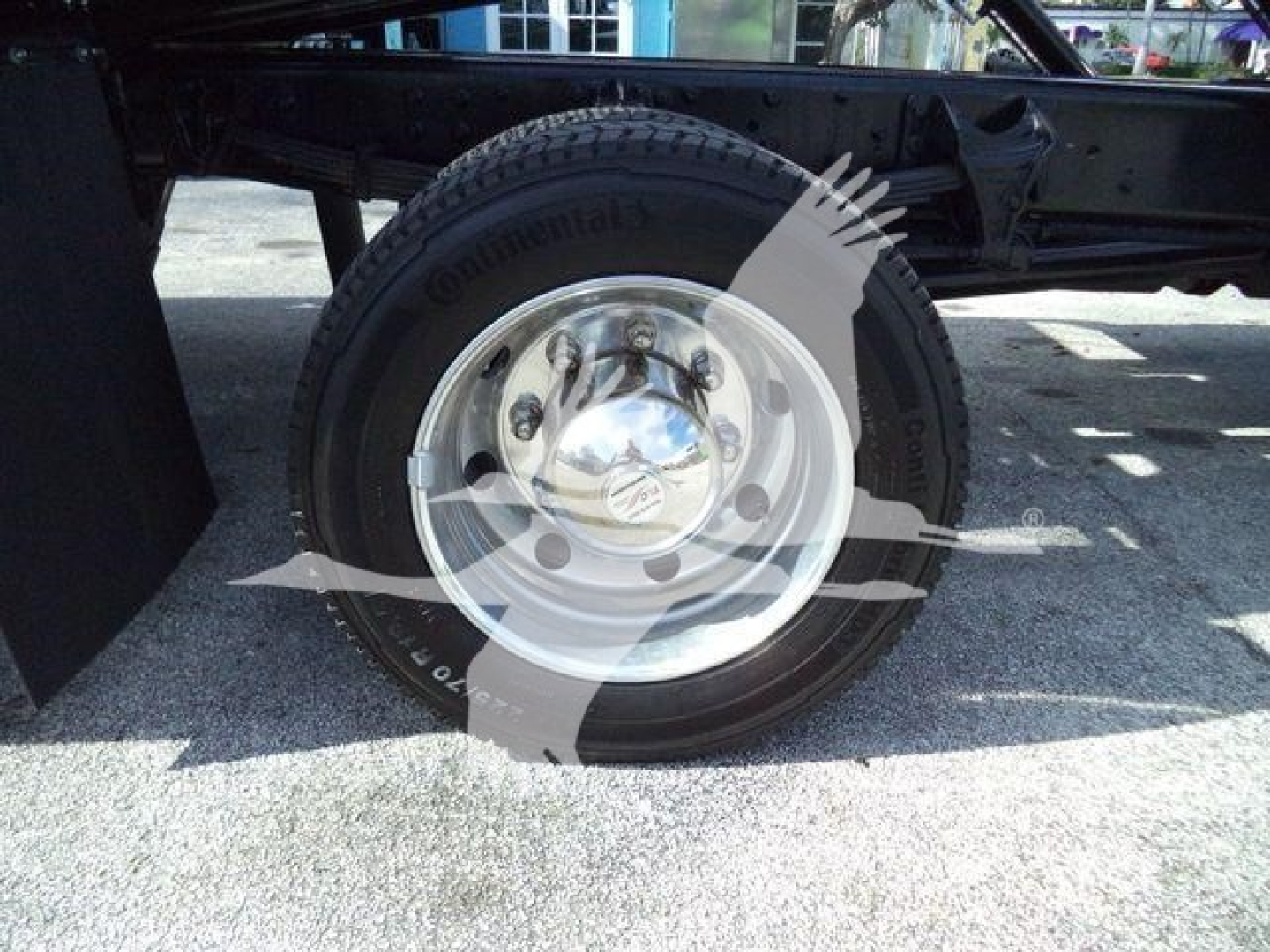 Truck wheel and tire on a CV International truck frame side view showing Continental tire and chrome hubcap.