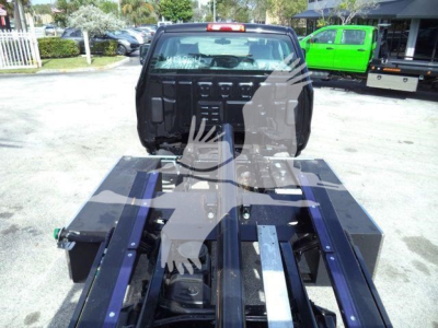 Truck chassis and cab area of a 2023 International CV rollback truck, view of the rear with the towing frame and storage boxes visible.