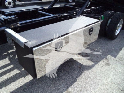 Truck chassis side showing a diamond plate toolbox mounted under the cab area next to rear wheels.