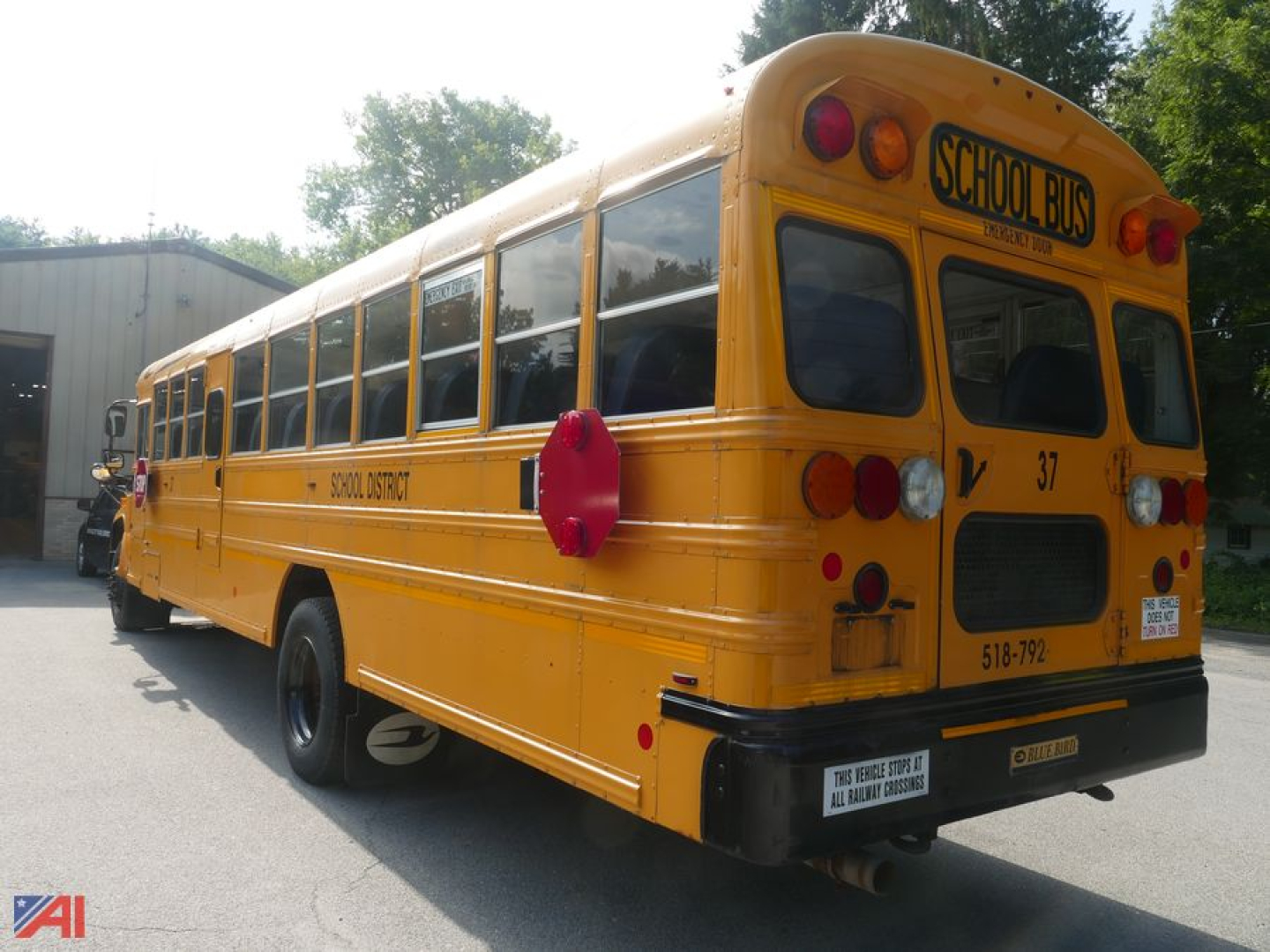 Yellow school bus rear view with 'SCHOOL BUS' sign on top rear window and bus number 37, blue bird branding, standard school bus tail lights, in-service exterior.