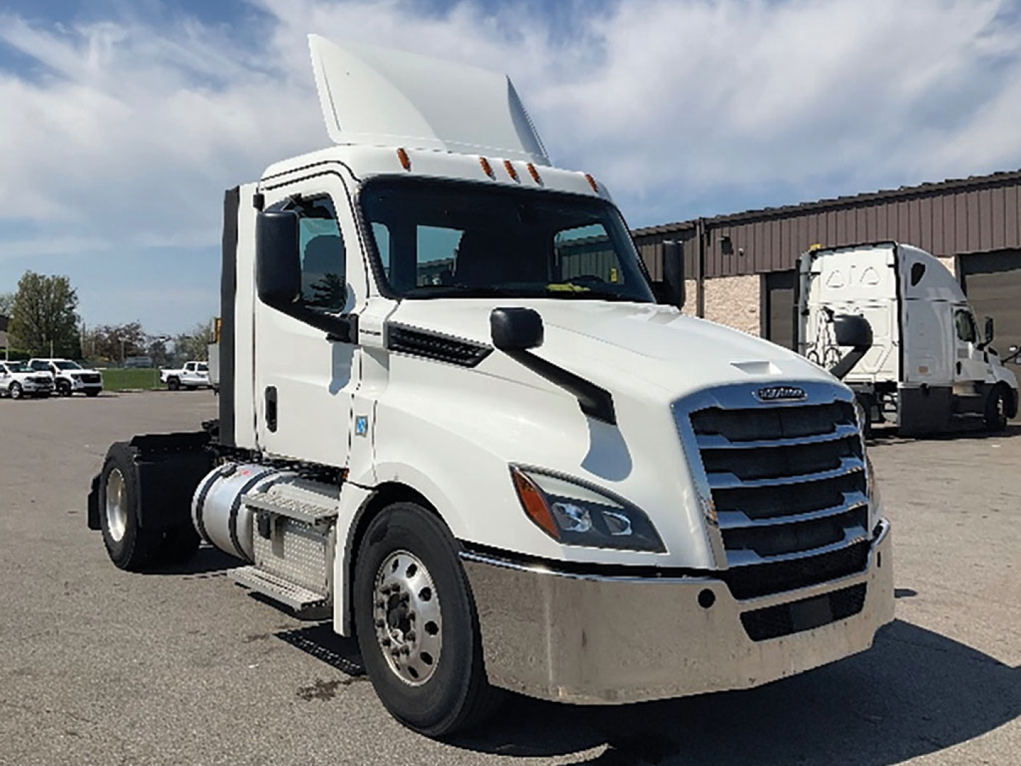 Freightliner Cascadia126 truck in a parking lot showing cab, grille, and raised sleeper with white exterior and black accents.