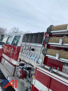 Fire engine/pumper side showing gauges, hoses, and compartments on a red and white International conventional cab fire truck.
