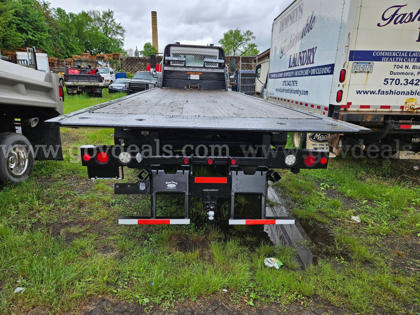 Flatbed tow truck bed of a 2015 Freightliner M2 106 with rear lights and hitch viewed from behind.