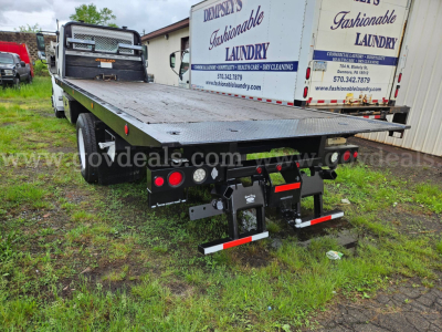 Freightliner M2 106 flatbed tow truck rear view showing hitch assembly, taillights, and mudflaps with reflective bars.