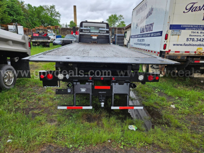 Flatbed tow truck bed of a 2015 Freightliner M2 106 with rear lights and hitch viewed from behind.