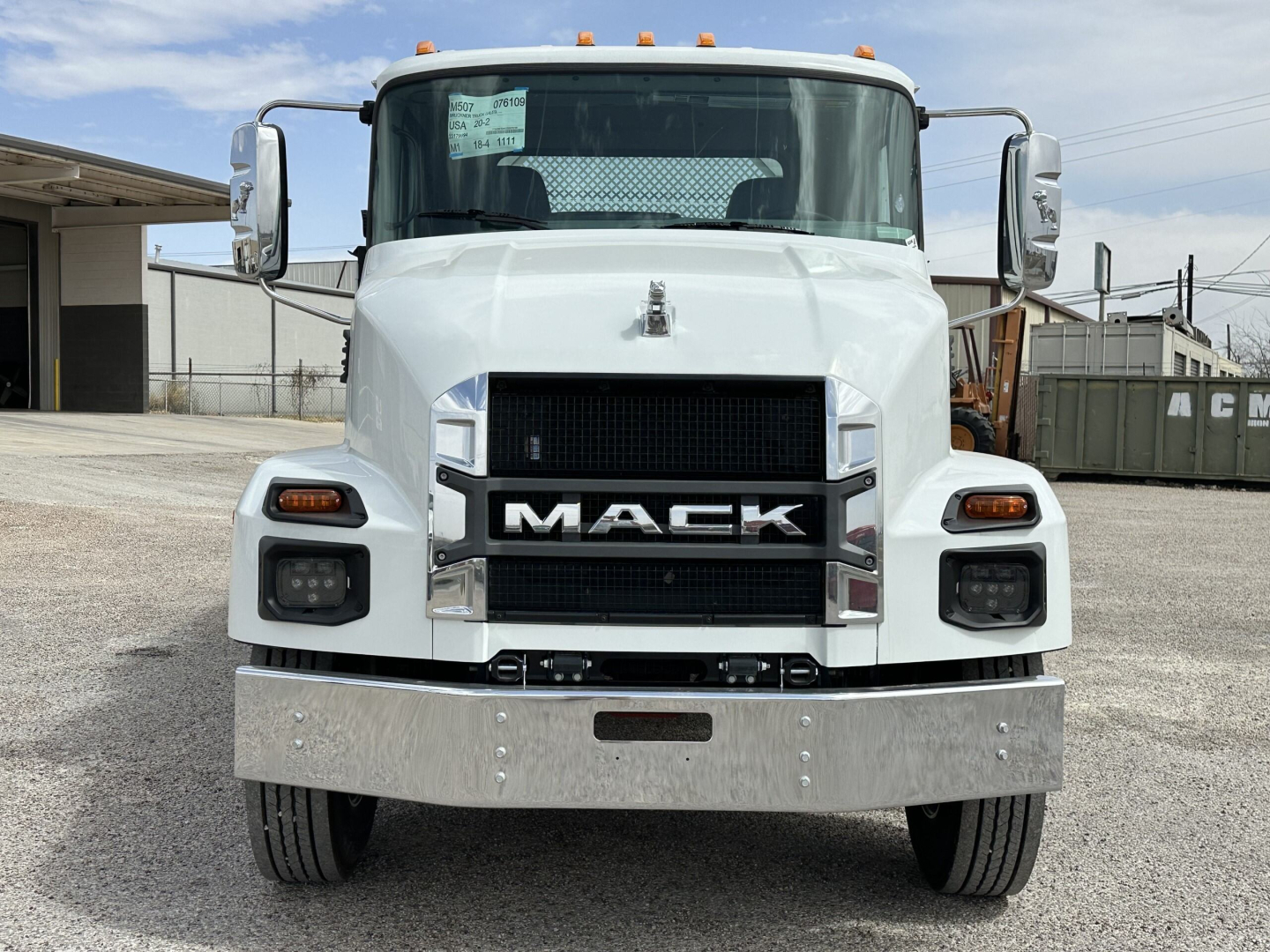 Front view of a new white 2025 Mack MD7 truck showing Mack grille, large bumper, and side mirrors.