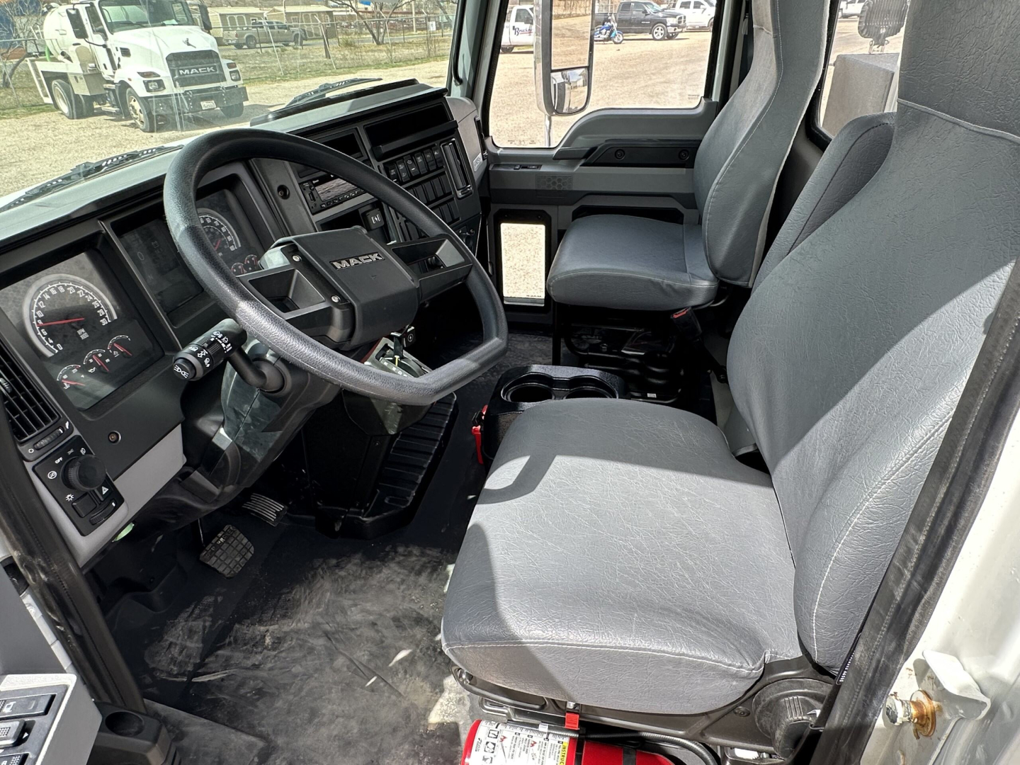 Cab interior of a 2025 Mack MD7 showing steering wheel, driver and passenger seats, dashboard with gauges, and center console.