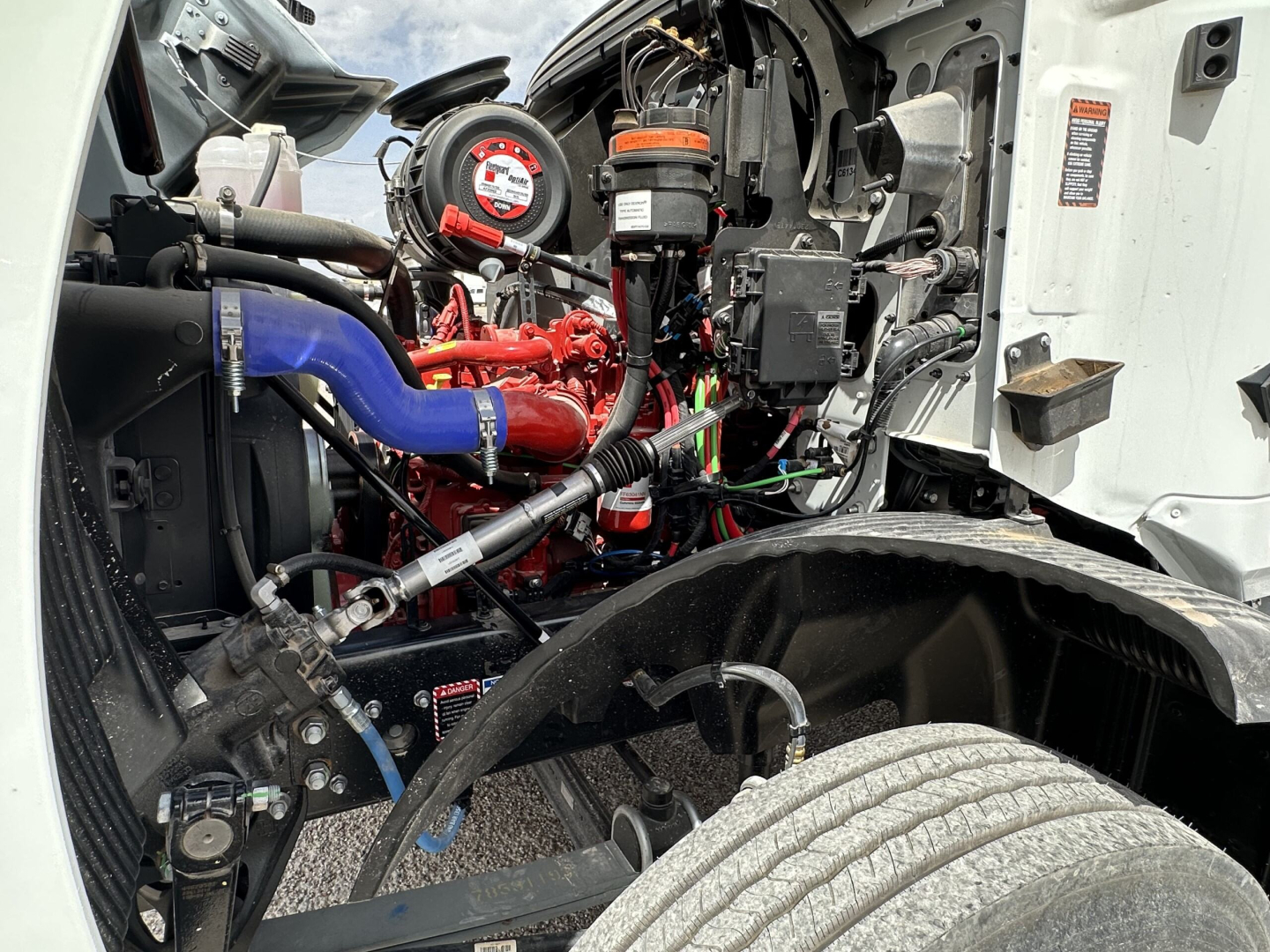 MD7 engine bay showing coolant hoses, red intake manifold, black air filter housing, and various hoses in a truck engine compartment.