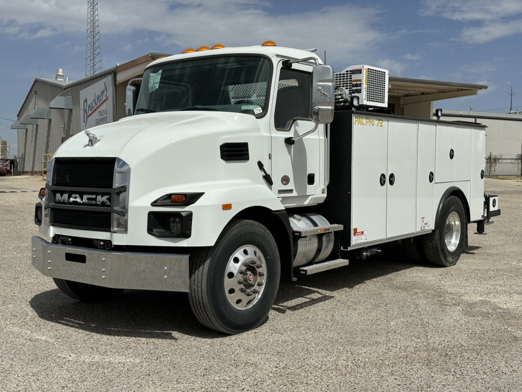 Mack MD7 service truck in a parking lot showing utility body with compartments and side equipment, front grille with MAC K branding, white cab, headlights, and amber clearance lights