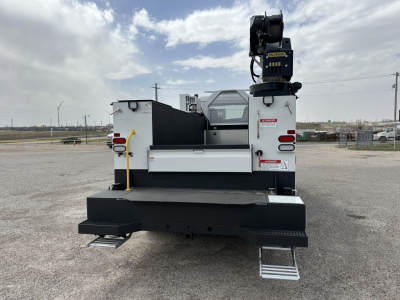 Equipment rear view of a 2025 Mack MD7 service truck showing crane, l-shape steps, and white body.