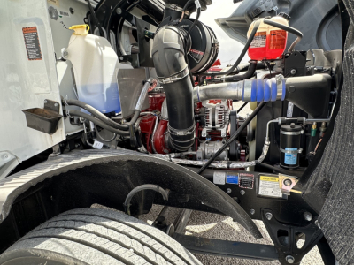 Mack MD7 engine bay showing coolant reservoir, turbo hoses, and intercooler piping with metal components and blue hose clamp.