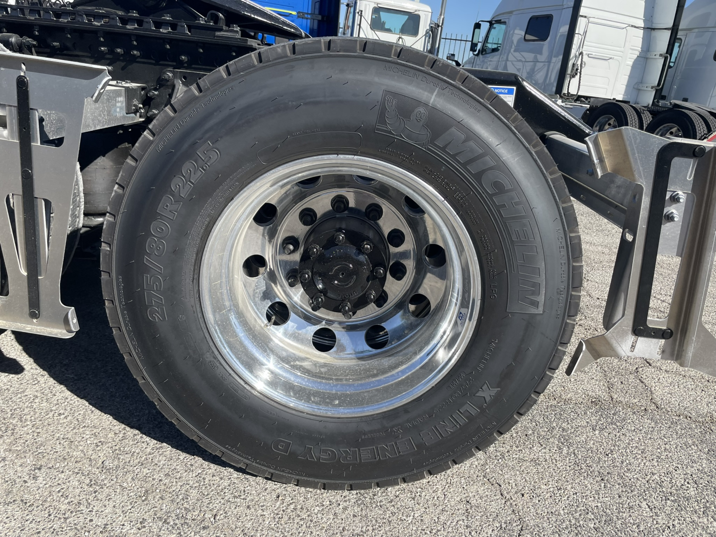 Volvo truck showing large single rear wheel/tire with metallic rim and hub, visible tire sidewall markings, part of chassis and fender area.