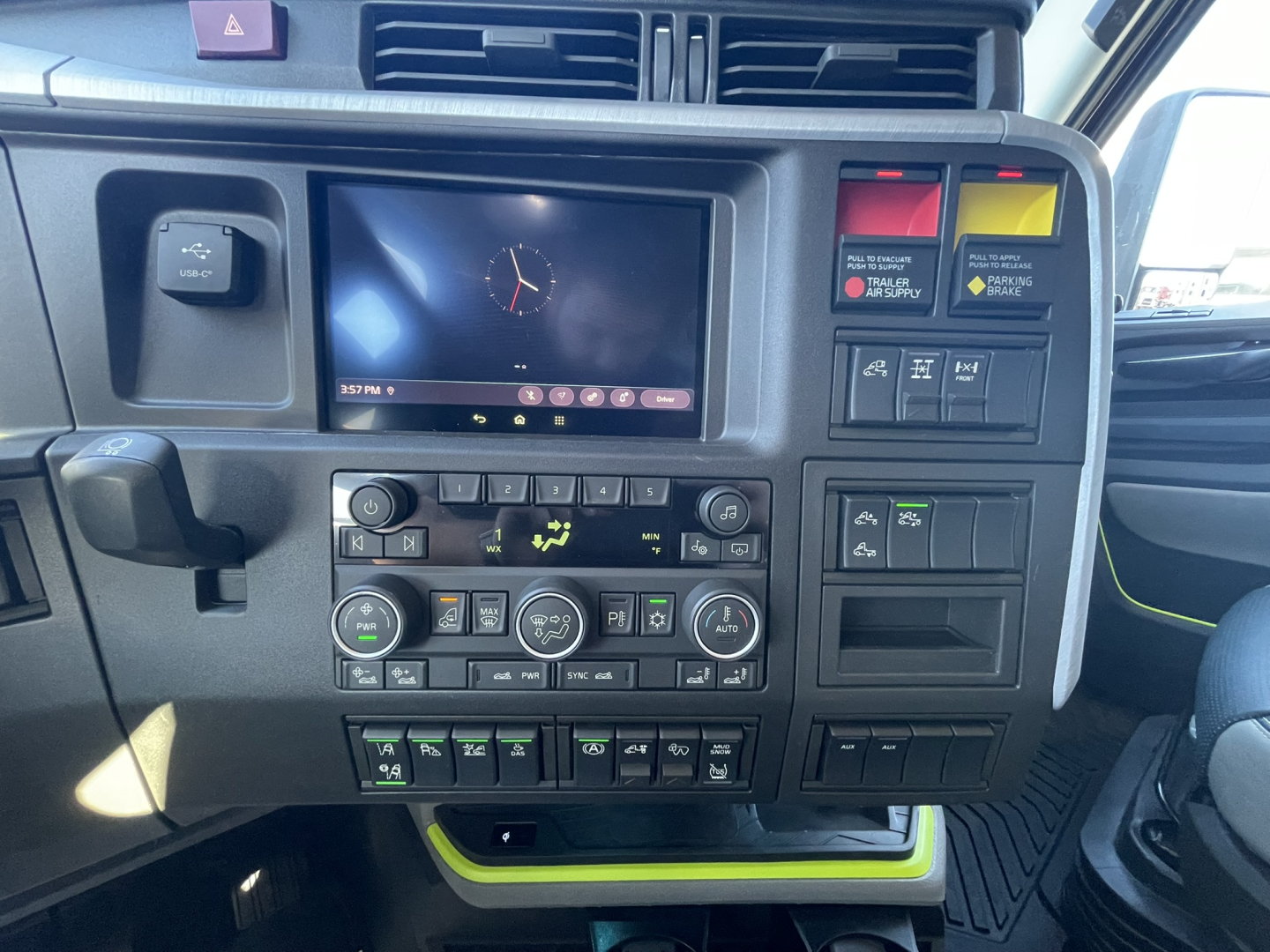 Dashboard of a Volvo VNL tractor cab showing multi-function display, climate controls, and labeled switches.