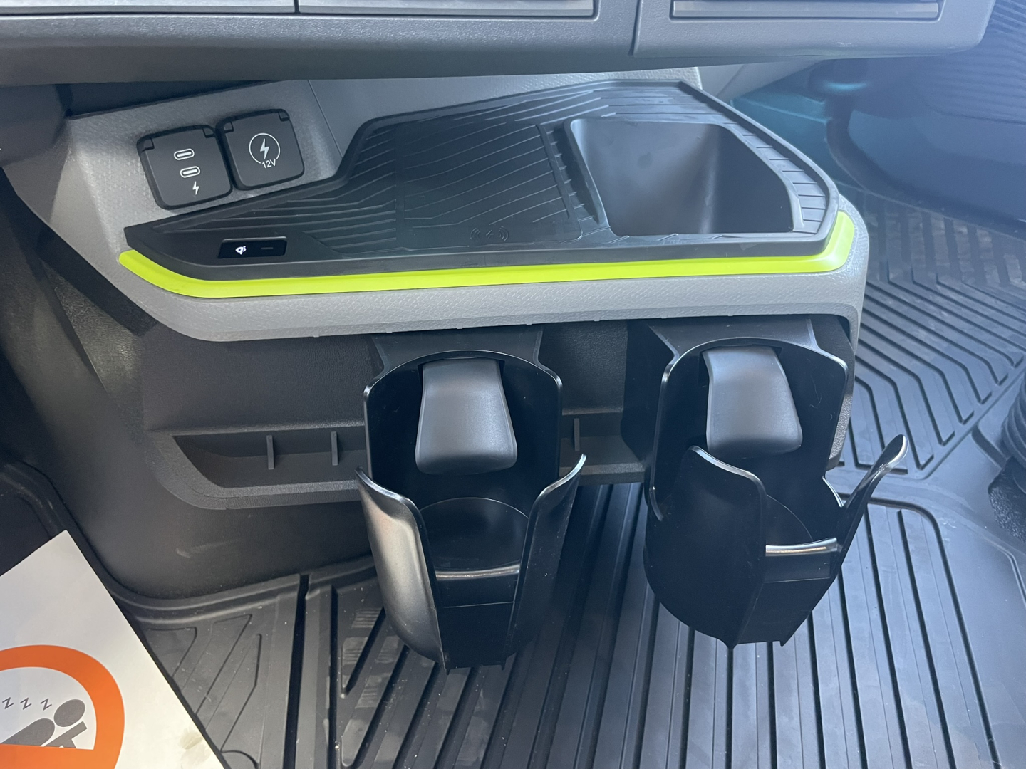 Interior of a Volvo VNL64T860 showing dual cup holders and center console with neon green accent strip and 12V/USB power switch