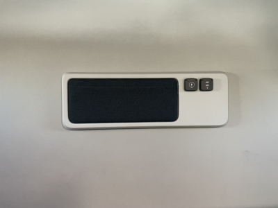 Air vent/reading light panel labeled with two small icons on the right side, mounted on a light gray wall.