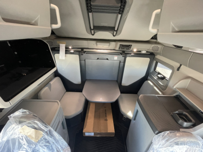 Cab interior of a new Volvo VNL truck showing seating area with table, overhead storage, and driver cabin panels.