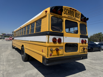 Yellow school bus rear view showing emergency door, brake lights, and school bus markings.