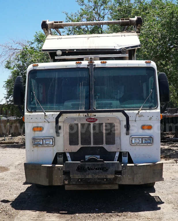 Front view of a white 2015 Peterbilt 320 garbage truck with a raised hydraulic loader, grille, and bumper, in-service condition.