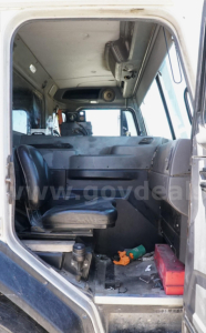 Truck cab interior view showing seats and dashboard of a Peterbilt 320, compact cabin with overhead storage and control panels.