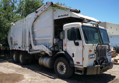 Vehicle side view of a white Peterbilt 320 garbage truck with a hydraulic loader, front cab, and rear waste collection body.