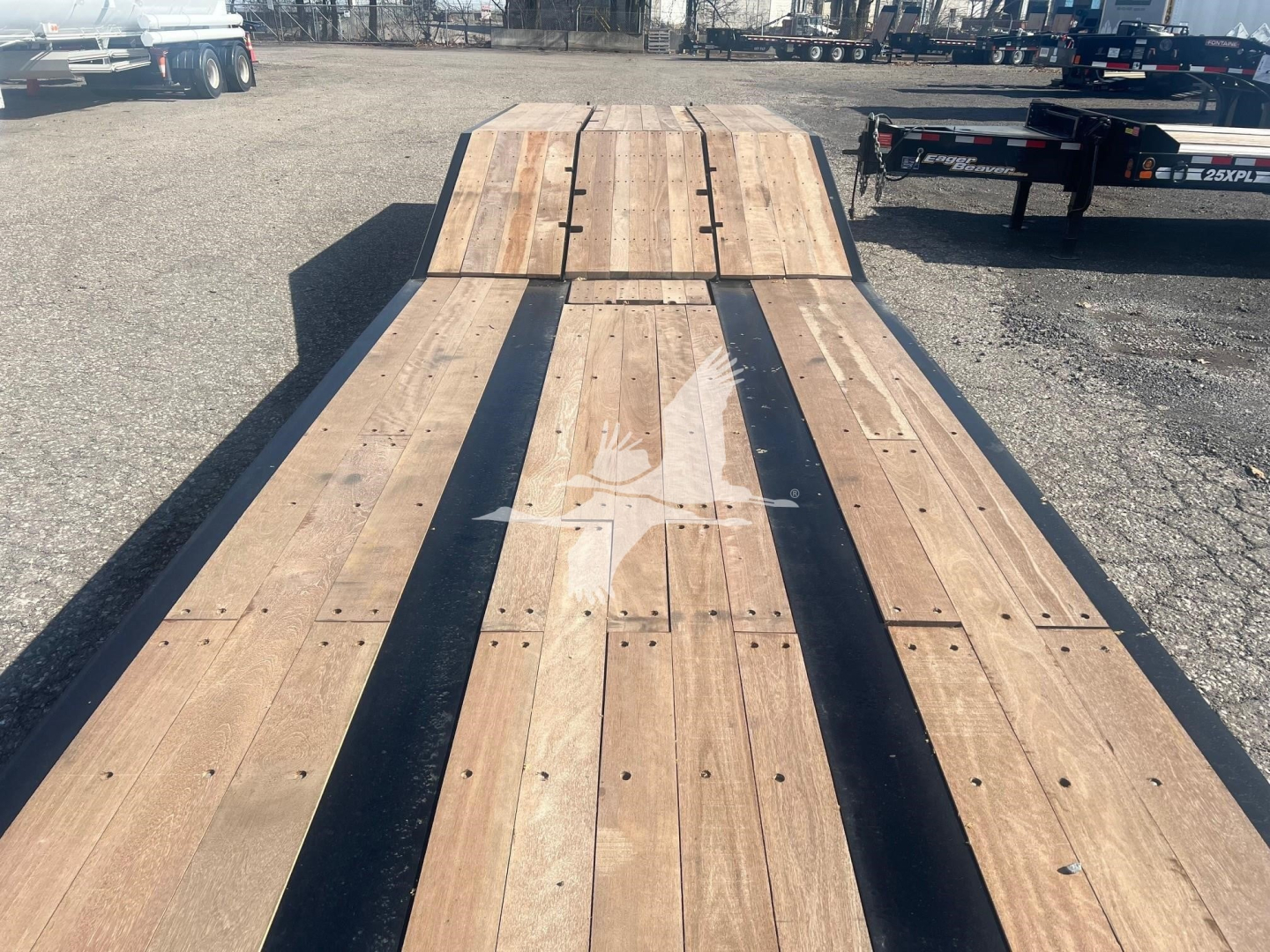 Trailer deck showing wooden planks on Fontaine Paver Pro lowboy trailer; view from front to rear with metal edge rails and tie-down points visible.