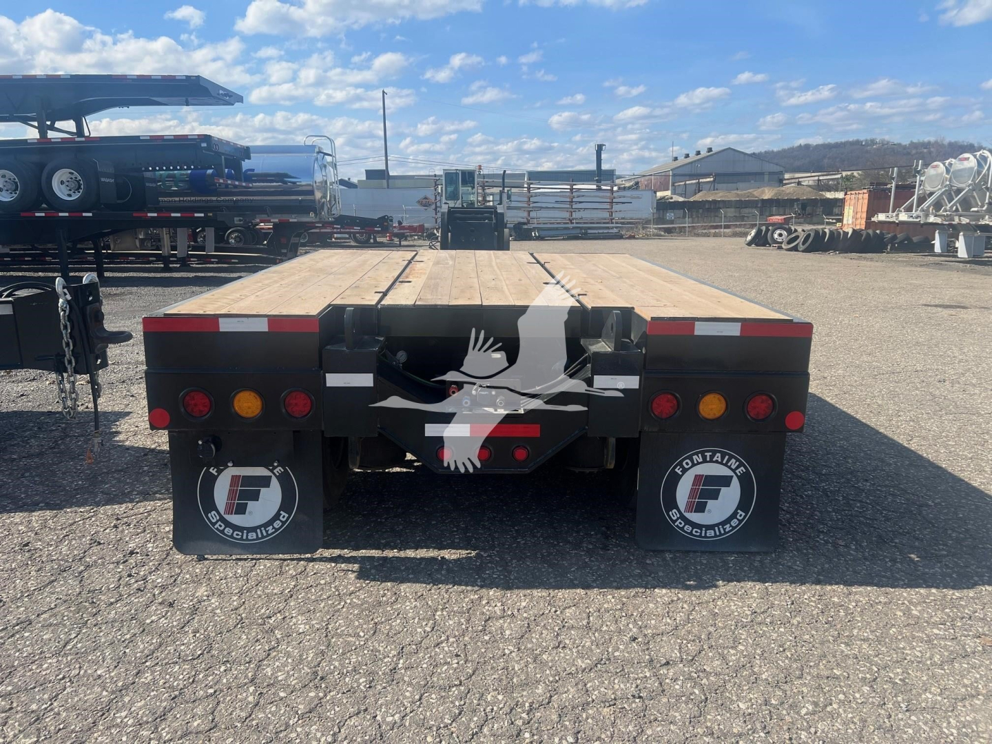 Fontaine Paver Pro lowboy trailer rear showing taillights, mudflaps with Fontaine logo, wooden deck, and rear bumper with safety markings.
