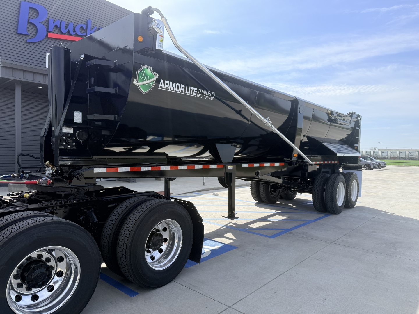 Armor Lite trailer showing 28/48 1/4 frame single point dump trailer with black body, dual rear axles, and logo reading Armor Lite Trailers. VIN on side.