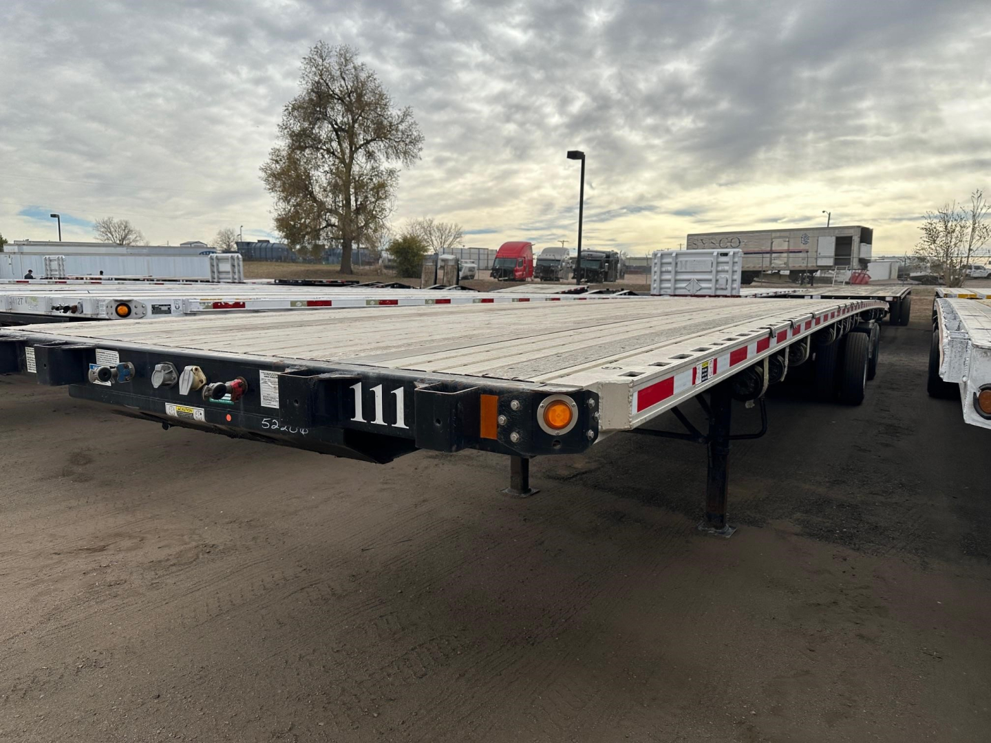 Flatbed trailer showing rear with bumper, lights, and support legs; number 111 on left side; reflective tape along rails; Fontaine branding not visible; wide trailer bed with metal surface.