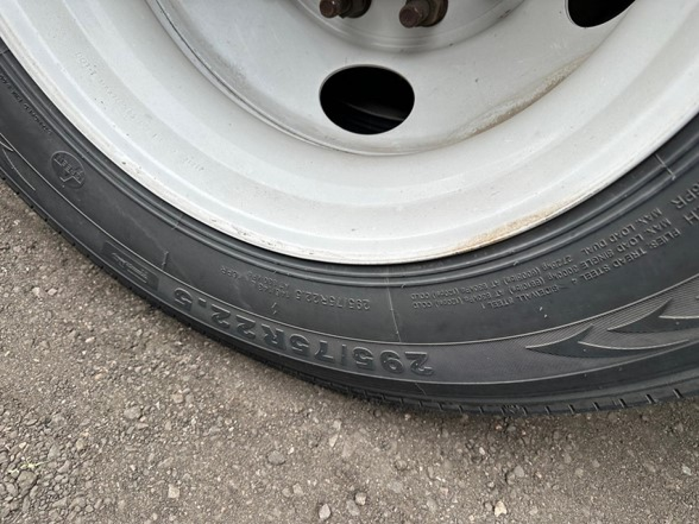 Trailer wheel and tire close-up showing tire sidewall markings and rim details.