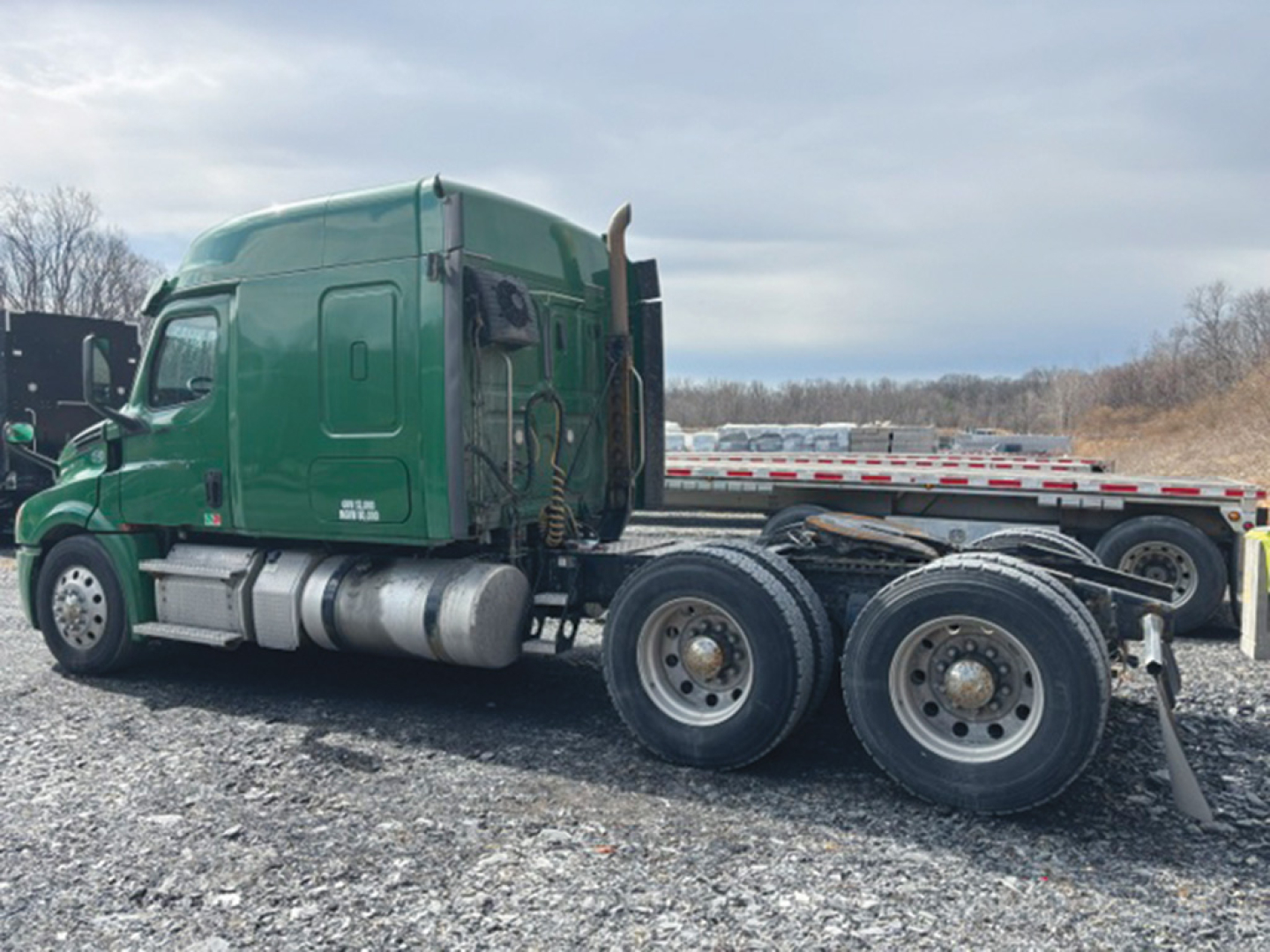 Freightliner Cascadia126 truck tractor side view showing green cab and dual rear axles with sleeper cab.
