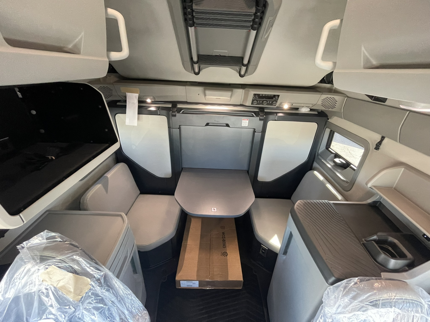 Volvo VNL64T860 cab interior showing sleeper area with table, overhead storage, and side consoles.
